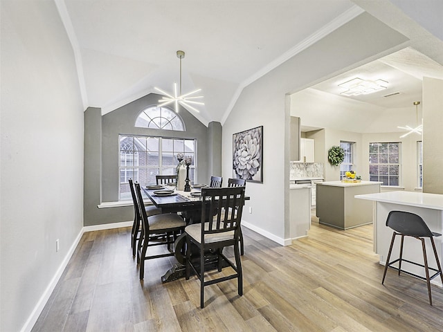 dining room with a chandelier, ornamental molding, vaulted ceiling, and light wood-type flooring