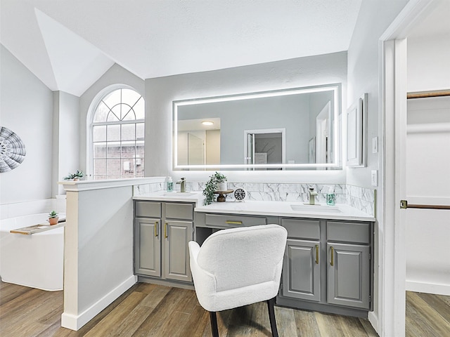 bathroom with vanity, wood-type flooring, and vaulted ceiling