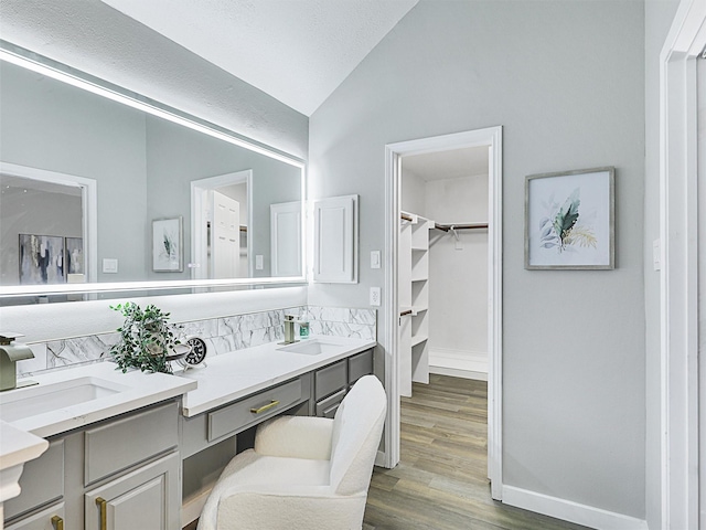 bathroom featuring vanity, wood-type flooring, and vaulted ceiling