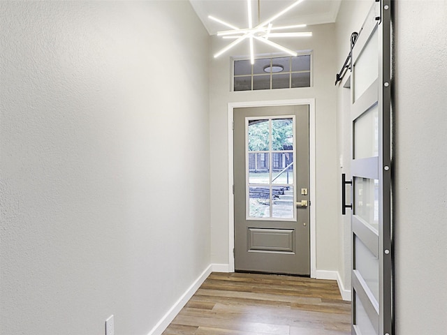 doorway featuring a chandelier, a barn door, and light hardwood / wood-style flooring