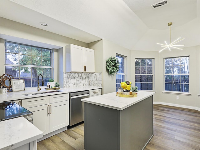 kitchen with dishwasher, white cabinets, sink, light wood-type flooring, and a kitchen island