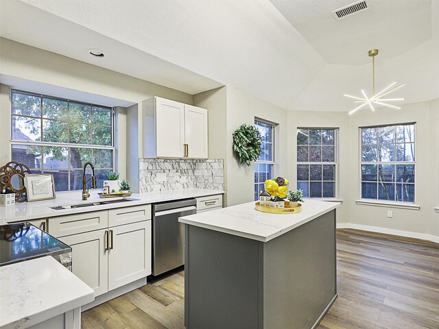 kitchen featuring sink, white cabinetry, light stone counters, a center island, and stainless steel dishwasher