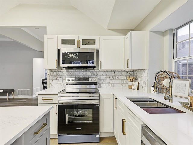 kitchen with decorative backsplash, white cabinets, and appliances with stainless steel finishes