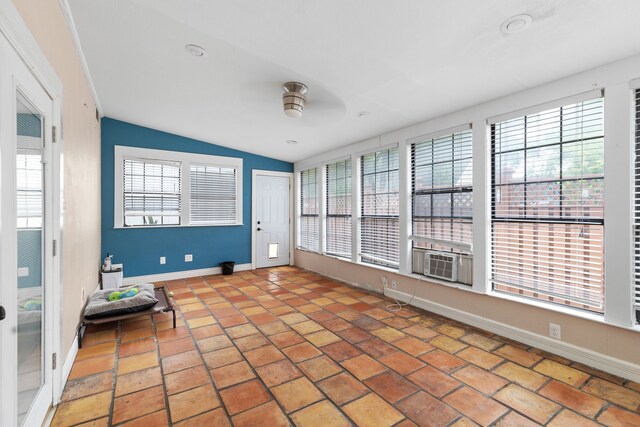 unfurnished sunroom featuring ceiling fan, a healthy amount of sunlight, lofted ceiling, and cooling unit