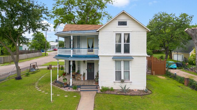 view of front facade featuring a front yard, a porch, and a balcony