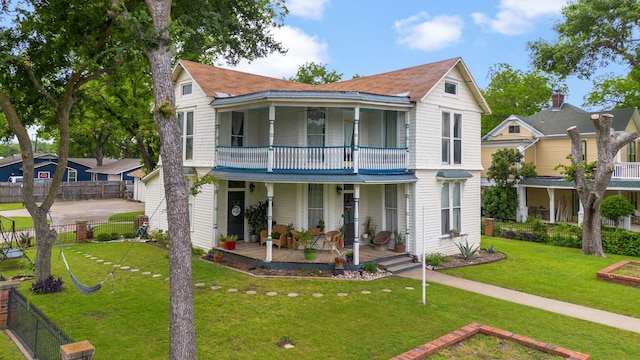 view of front of house featuring covered porch, a balcony, and a front yard