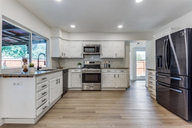 kitchen featuring a healthy amount of sunlight, light stone counters, sink, and appliances with stainless steel finishes