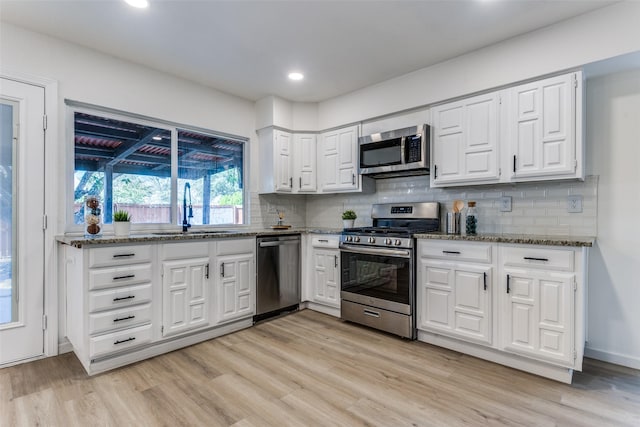 kitchen with white cabinets, sink, light hardwood / wood-style flooring, tasteful backsplash, and stainless steel appliances