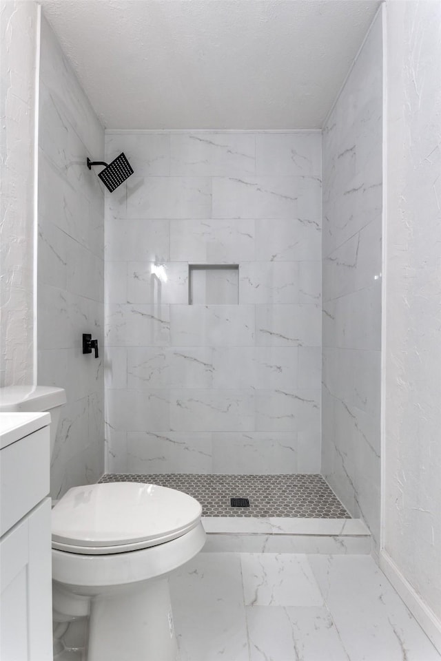 bathroom featuring vanity, toilet, and tiled shower