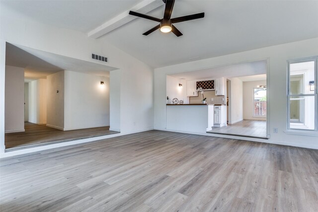 unfurnished living room with lofted ceiling with beams, light hardwood / wood-style floors, ceiling fan, and indoor bar