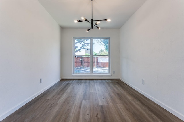 unfurnished room featuring a chandelier and dark hardwood / wood-style floors