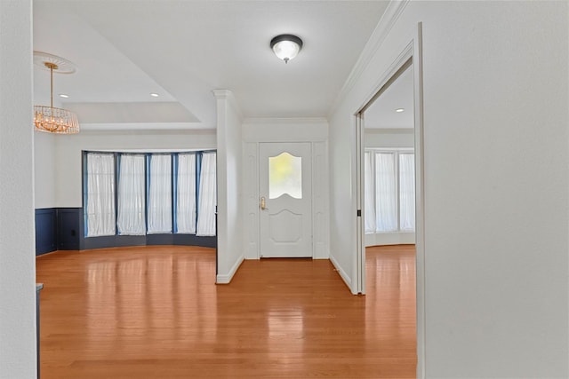 foyer with an inviting chandelier, ornamental molding, and light hardwood / wood-style flooring