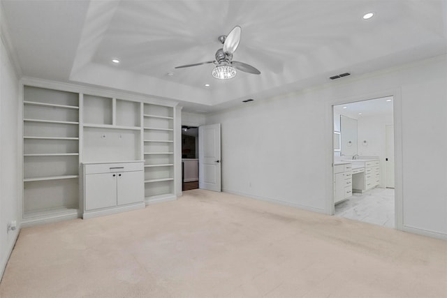 carpeted bedroom with ceiling fan, ensuite bath, and a raised ceiling