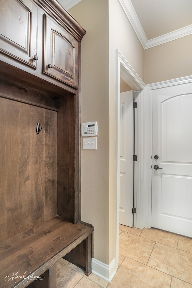 mudroom with crown molding and light tile patterned floors