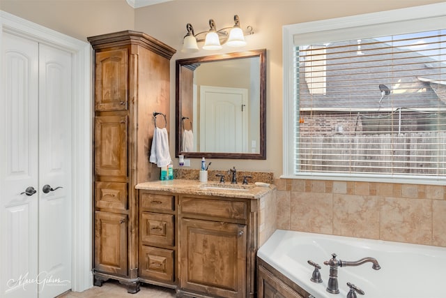 bathroom featuring a tub, vanity, and a healthy amount of sunlight