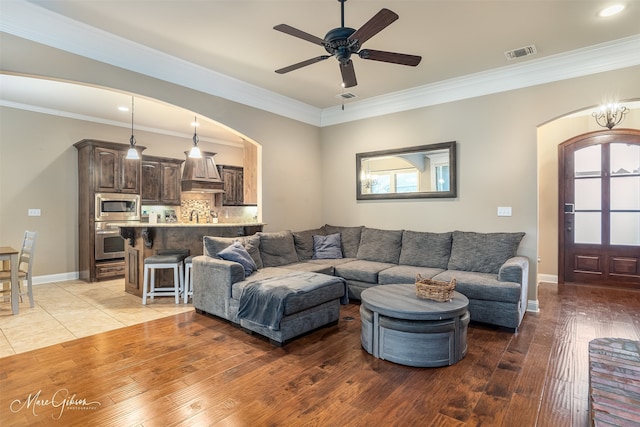 living room featuring plenty of natural light, light hardwood / wood-style floors, ornamental molding, and ceiling fan