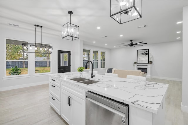 kitchen with pendant lighting, dishwasher, a kitchen island with sink, white cabinets, and sink