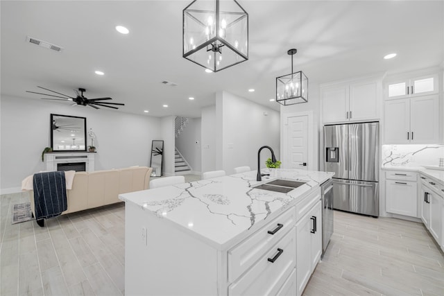 kitchen featuring appliances with stainless steel finishes, white cabinetry, pendant lighting, and an island with sink