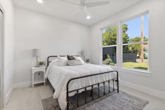 bedroom featuring ceiling fan, light hardwood / wood-style floors, and multiple windows