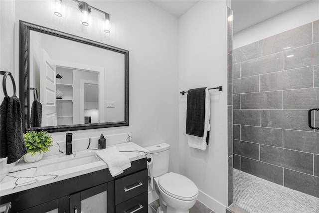 bathroom with vanity, toilet, and tiled shower