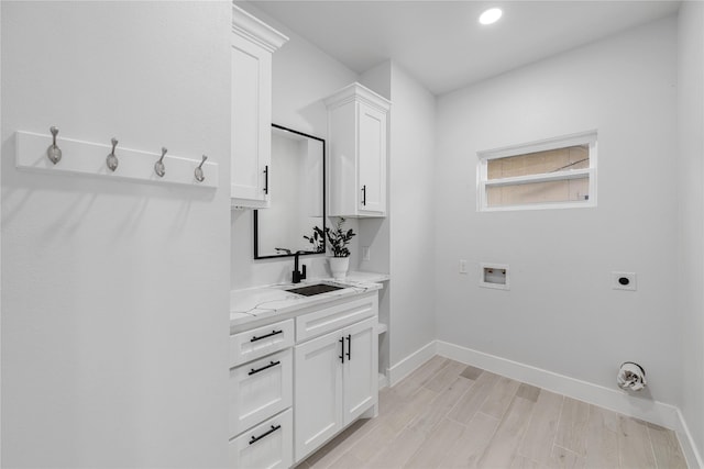 washroom featuring cabinets, hookup for a washing machine, electric dryer hookup, sink, and light hardwood / wood-style floors