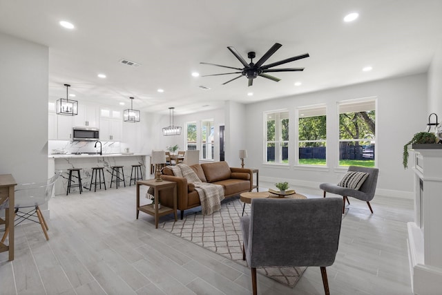 living room with ceiling fan, a healthy amount of sunlight, and light wood-type flooring