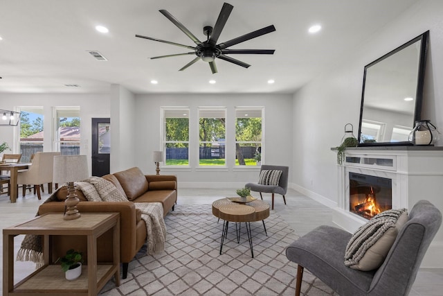 living room with ceiling fan, plenty of natural light, a high end fireplace, and light hardwood / wood-style flooring