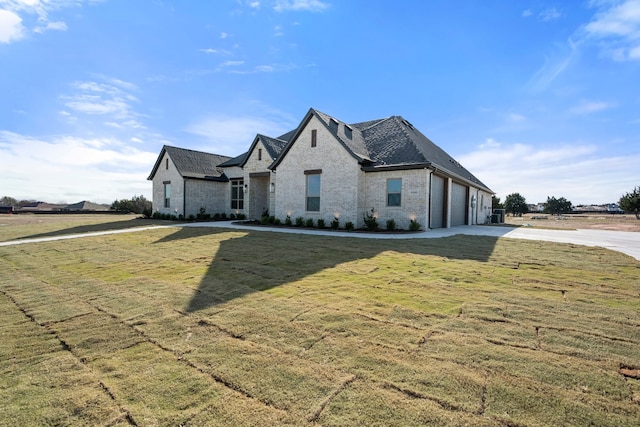 french provincial home with a front lawn and a garage