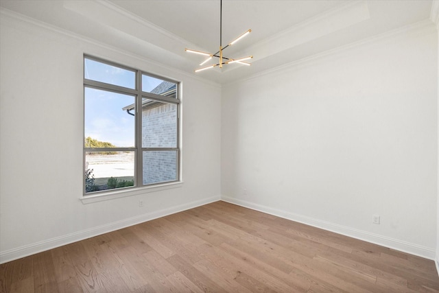 unfurnished room featuring ornamental molding, light wood-type flooring, a raised ceiling, and a chandelier