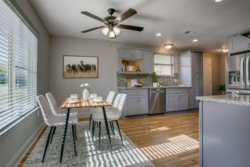 kitchen featuring sink, light hardwood / wood-style flooring, appliances with stainless steel finishes, gray cabinets, and decorative backsplash