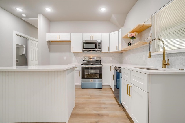 kitchen featuring appliances with stainless steel finishes, tasteful backsplash, sink, light hardwood / wood-style floors, and white cabinetry