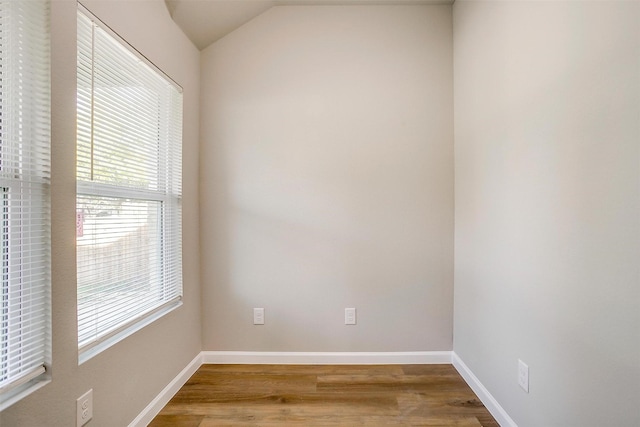 empty room with wood-type flooring and vaulted ceiling