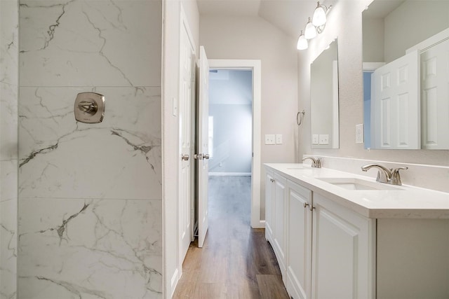 bathroom with hardwood / wood-style flooring, tiled shower, and vanity