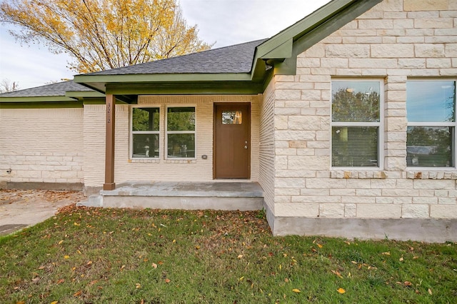 view of exterior entry with a yard and covered porch