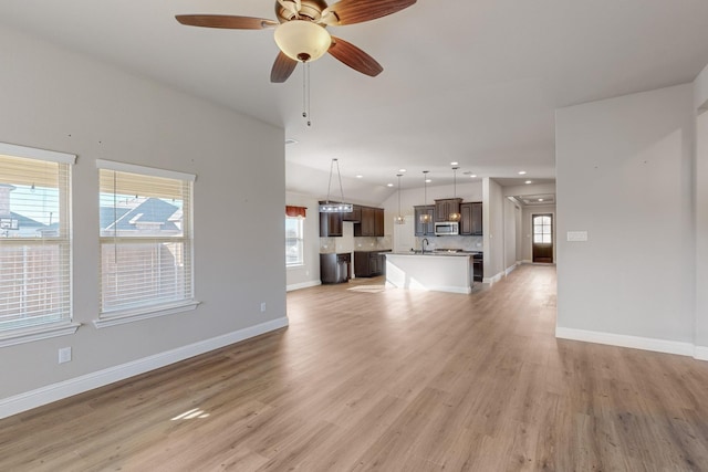 unfurnished living room with ceiling fan, a healthy amount of sunlight, and light wood-type flooring