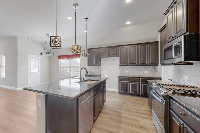 kitchen featuring stone counters, appliances with stainless steel finishes, sink, a kitchen island with sink, and dark brown cabinetry