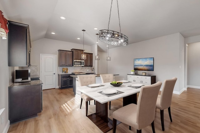 dining space with lofted ceiling, sink, and light hardwood / wood-style flooring