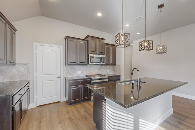 kitchen with an island with sink, appliances with stainless steel finishes, sink, and dark brown cabinets