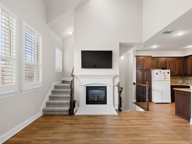 kitchen with backsplash, white fridge, high vaulted ceiling, and light wood-type flooring