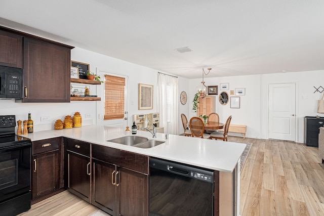 kitchen with black appliances, sink, dark brown cabinets, light hardwood / wood-style floors, and kitchen peninsula