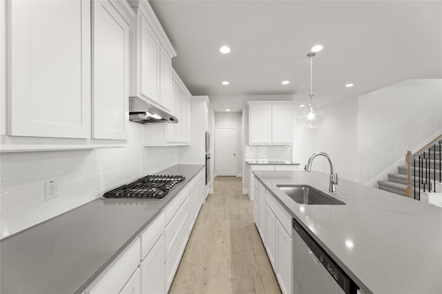kitchen with a sink, light wood-style floors, under cabinet range hood, recessed lighting, and stainless steel appliances