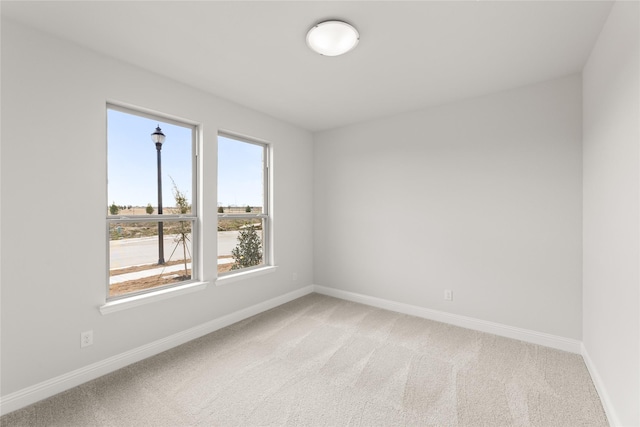 spare room with light carpet and baseboards