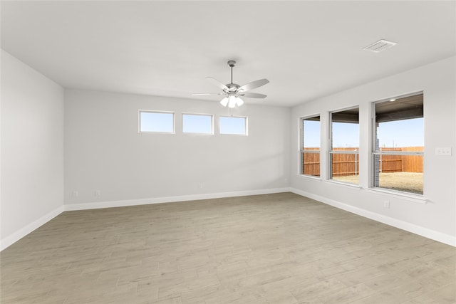 empty room with light wood-style flooring, baseboards, a ceiling fan, and visible vents