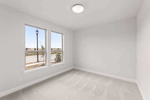 spare room with baseboards and light carpet