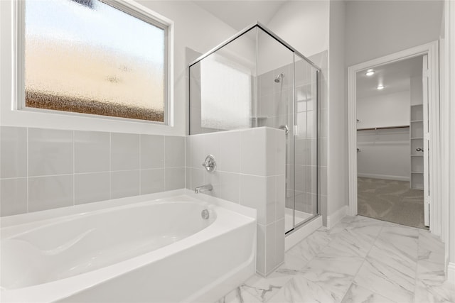bathroom featuring a shower stall, a bath, marble finish floor, and a spacious closet