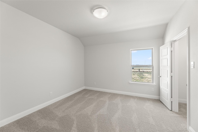 unfurnished bedroom featuring light carpet, baseboards, and lofted ceiling