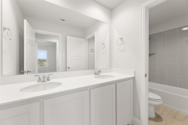 bathroom with a sink, toilet, double vanity, and bathing tub / shower combination