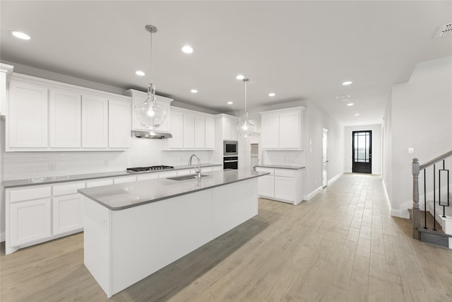 kitchen featuring recessed lighting, an island with sink, under cabinet range hood, appliances with stainless steel finishes, and a sink