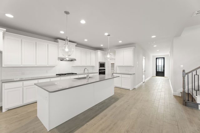 kitchen with recessed lighting, under cabinet range hood, a center island with sink, appliances with stainless steel finishes, and a sink