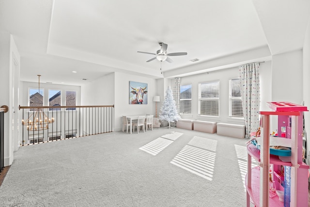 rec room featuring ceiling fan with notable chandelier, a raised ceiling, and carpet floors